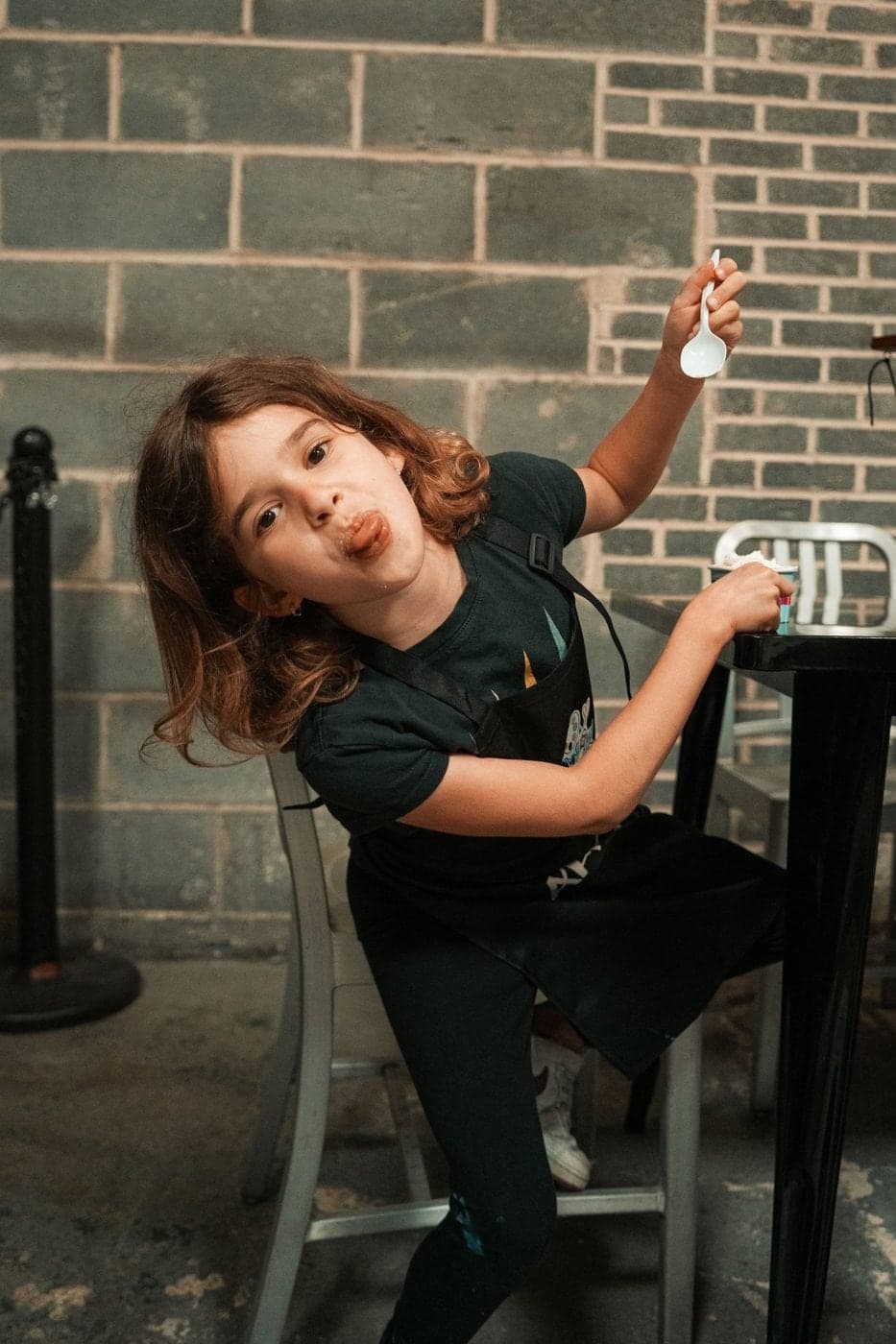 Alessia striking a playful pose in front of a brick wall